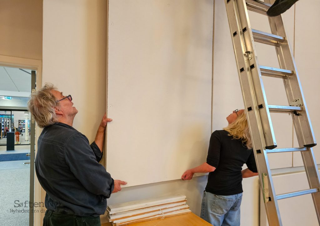 De hvide plader, der skal bære de 42 tegninger skal helt på plads, inden tegningerne sættes op, og kunstneren Max Parylewicz hjælper selv til. Foto: Anders Godtfred-Rasmussen - Søften Nyt.