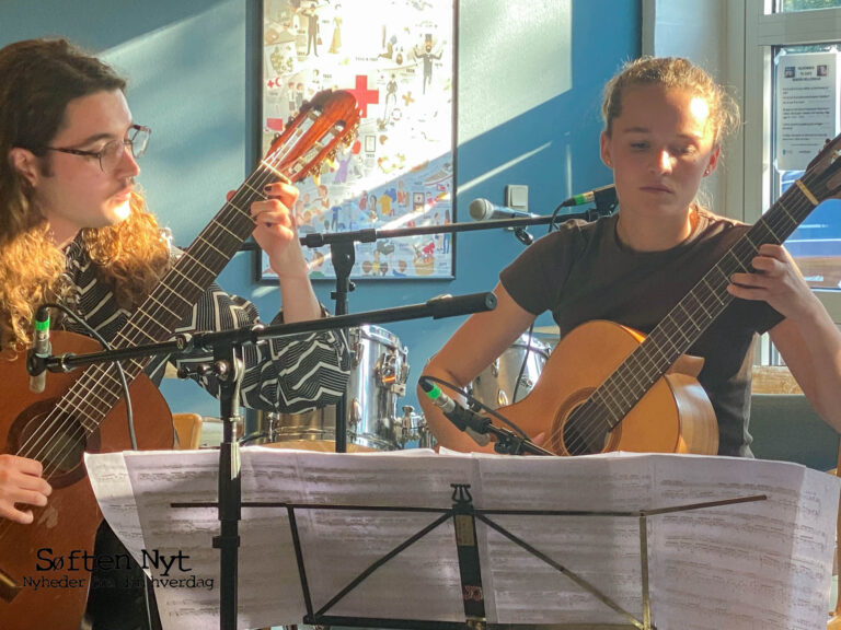 Billedet viser to mennesker der spiller på klassisk guitar. De har et nodestativ foran sig, mens de spiller og koncentrerer sig. Foto: Emilie Skov Dalgaard.