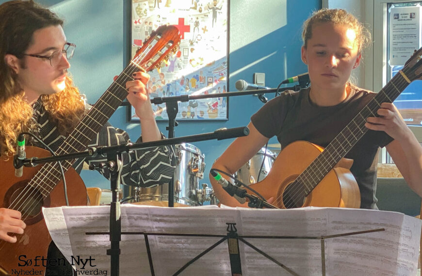 Billedet viser to mennesker der spiller på klassisk guitar. De har et nodestativ foran sig, mens de spiller og koncentrerer sig. Foto: Emilie Skov Dalgaard.